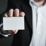 A man in a suit presenting a blank business card for corporate usage.